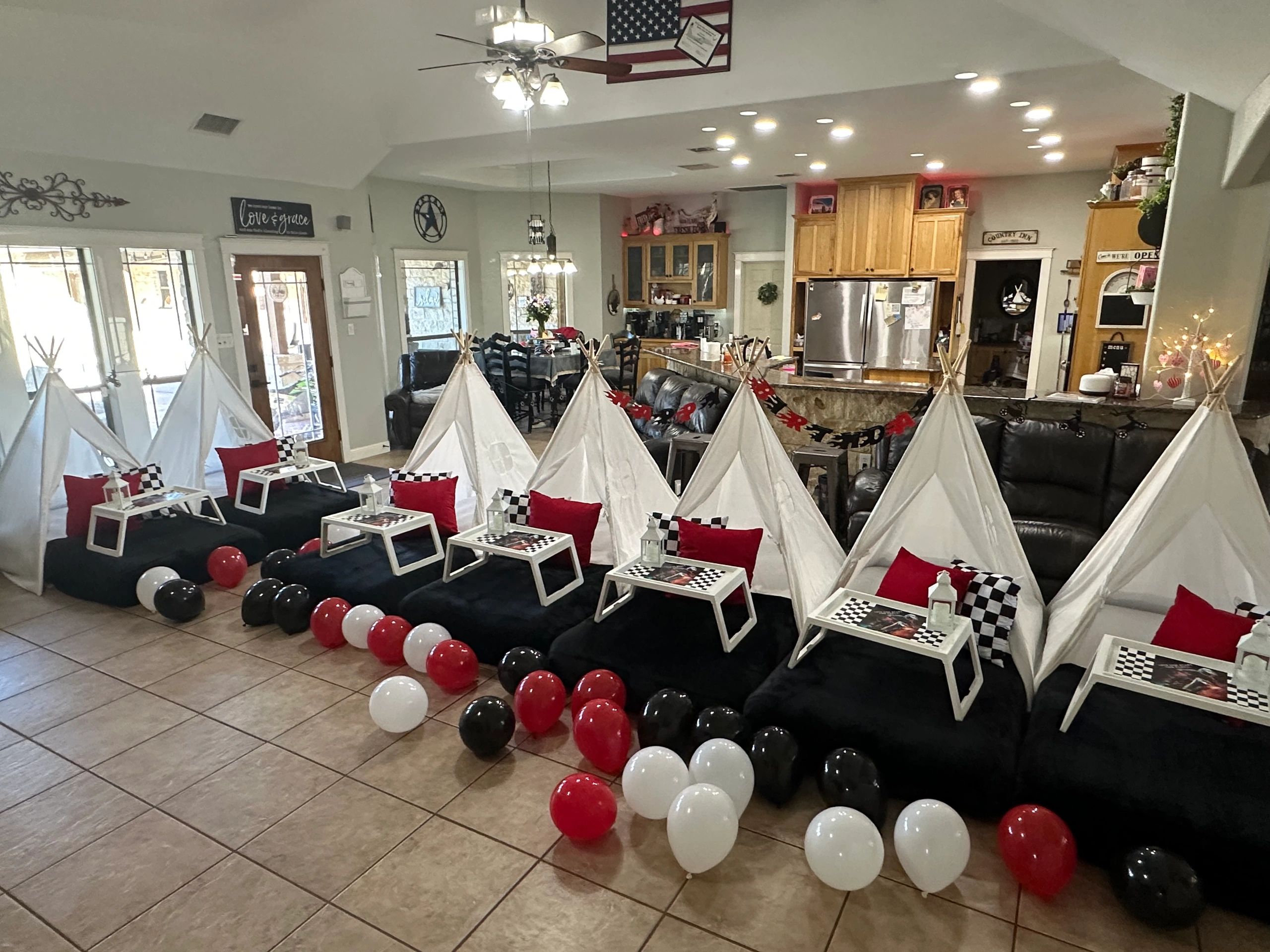 Indoor kids' sleepover setup with mini teepees, pillows, tables, and balloons.