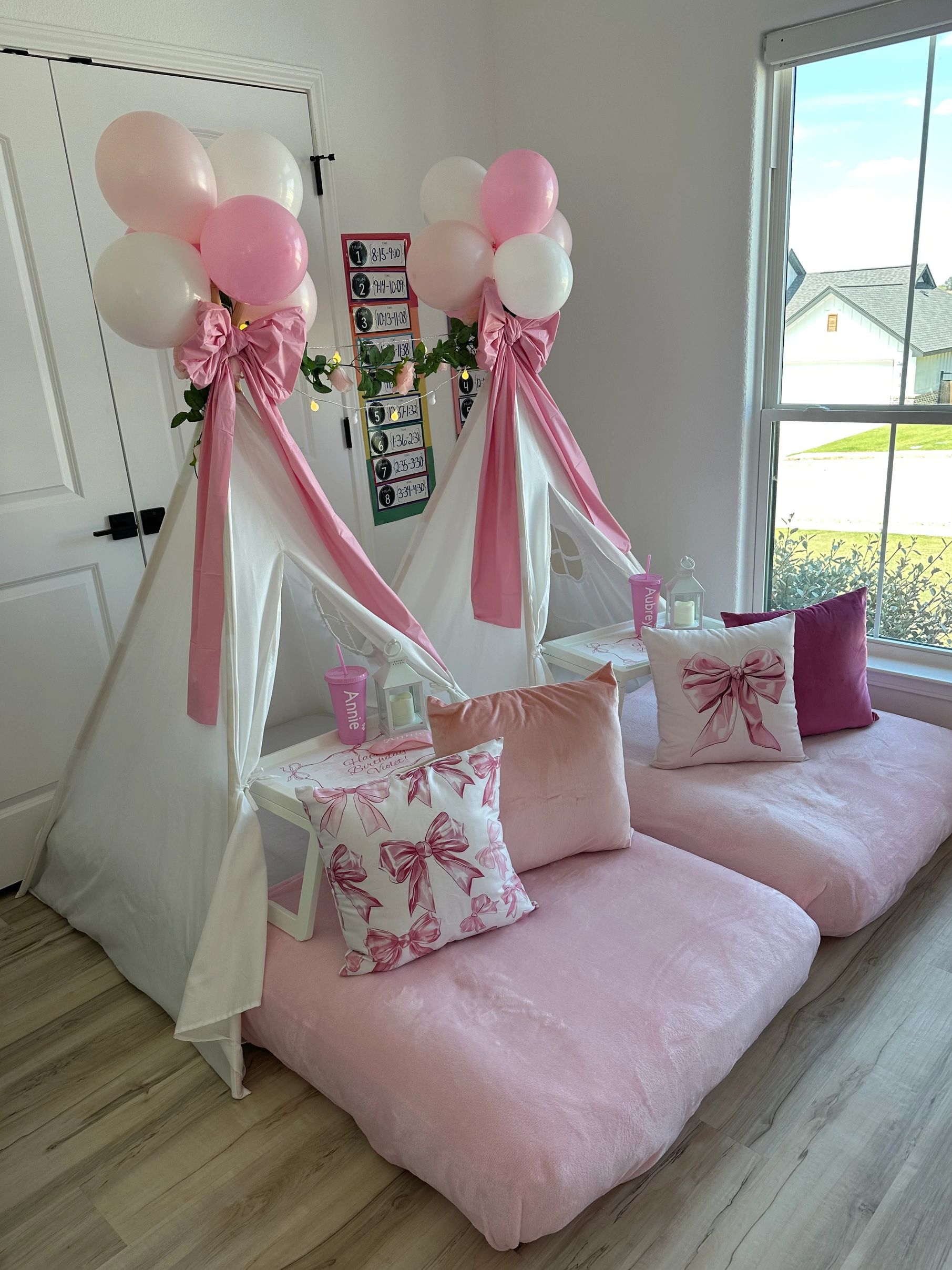 Cozy indoor teepees decorated with pink and white balloons and bows for a party.