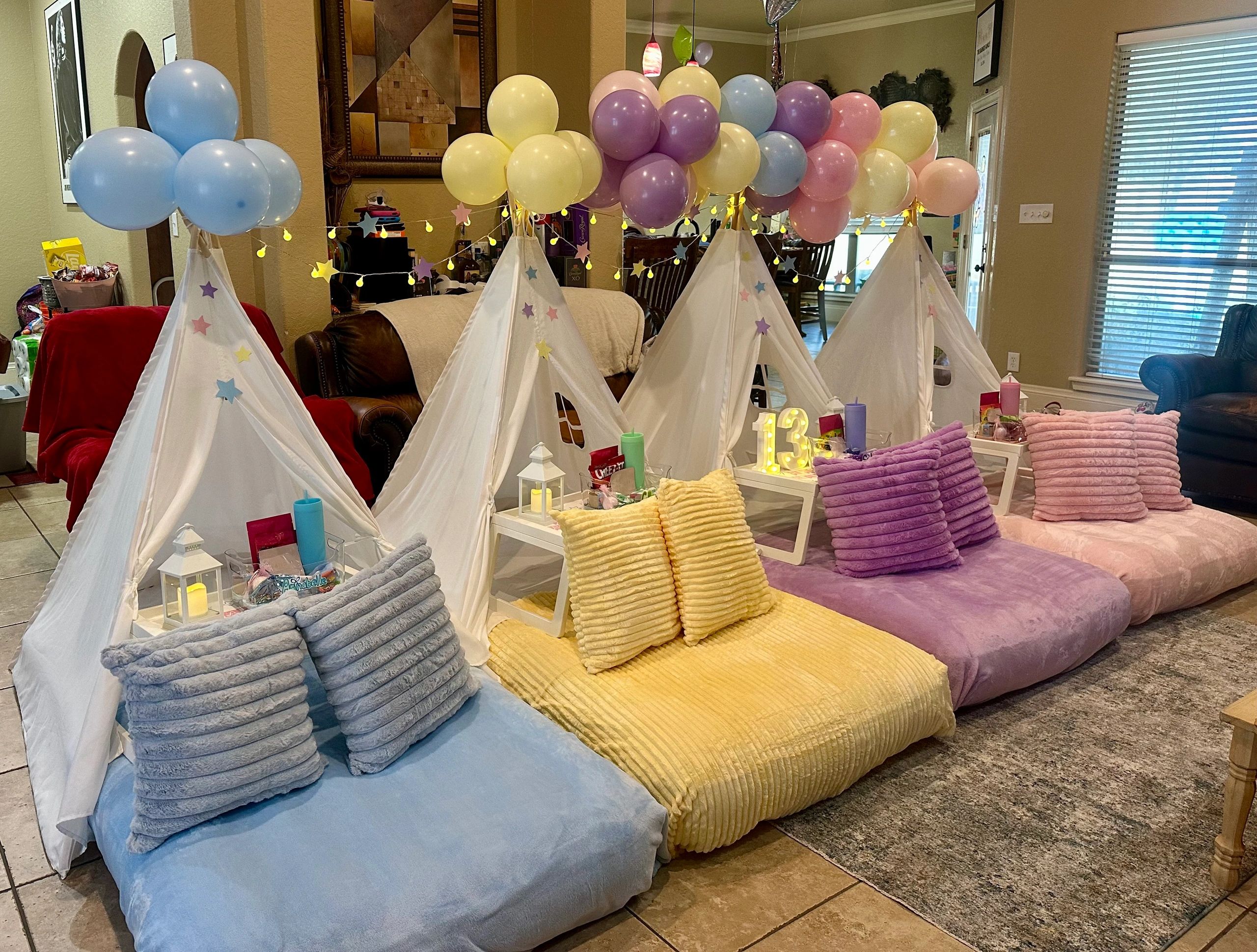 Cozy indoor slumber party setup with colorful pillows, tents, and balloons.