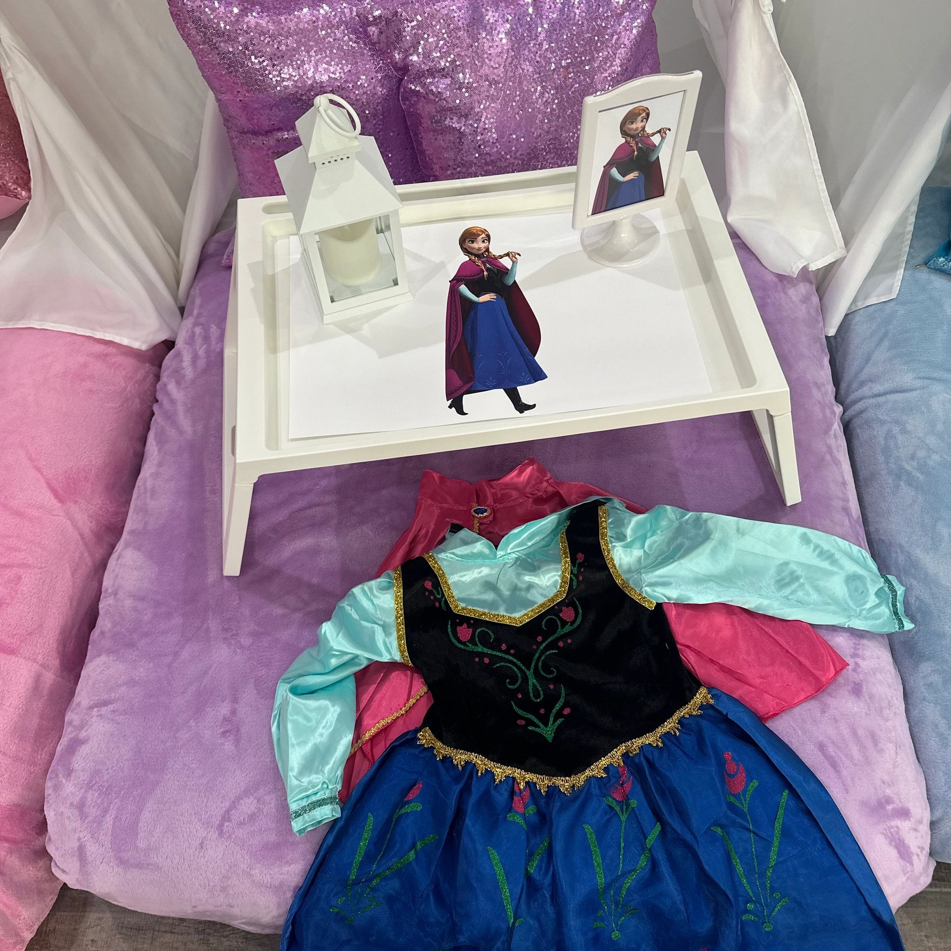 Children's Frozen-themed dress and tray with character images on a purple and pink plush surface.