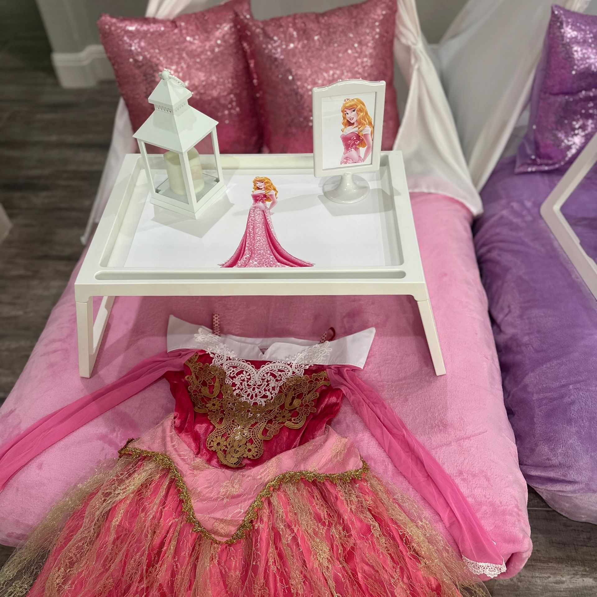 Princess-themed pink dress with matching decor on a tray and sparkly pillows in the background.