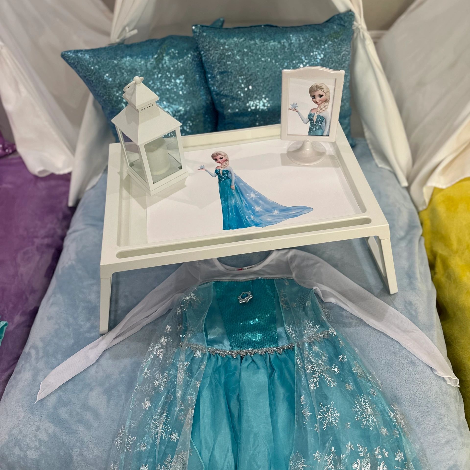 Frozen-themed setup with Elsa's dress and decorative items on a white tray.