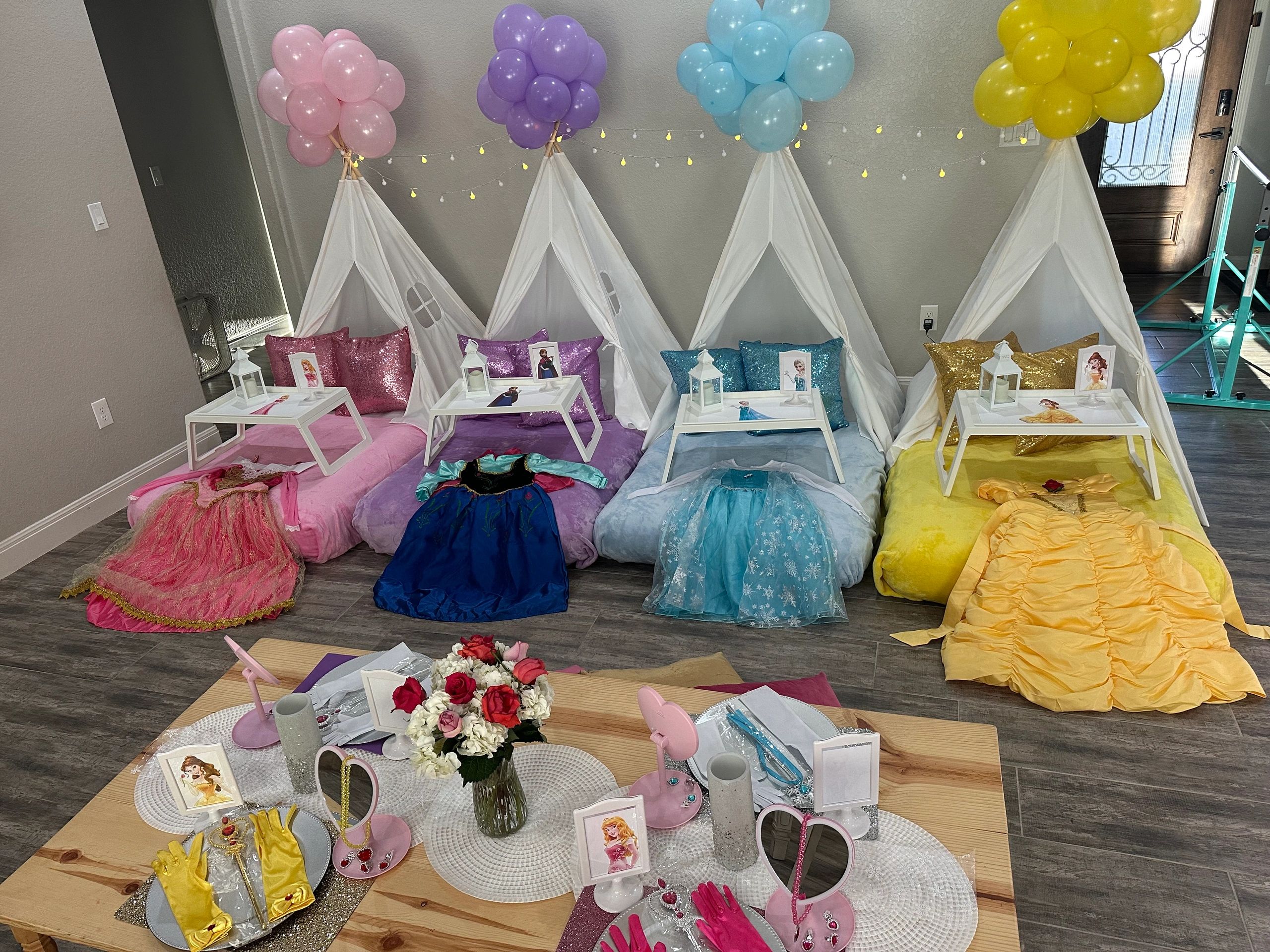 Colorful princess-themed sleepover setup with tents and dresses.