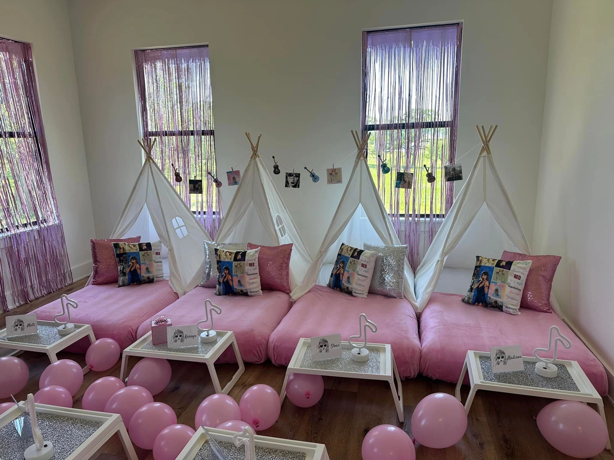 Cozy pink sleepover setup with teepees, pillows, and balloons.