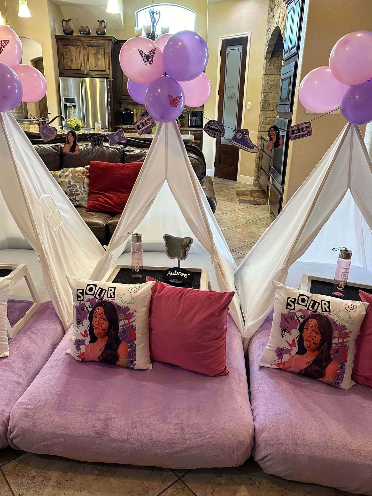 Cozy indoor tents with purple and pink balloons and themed pillows for a fun gathering.