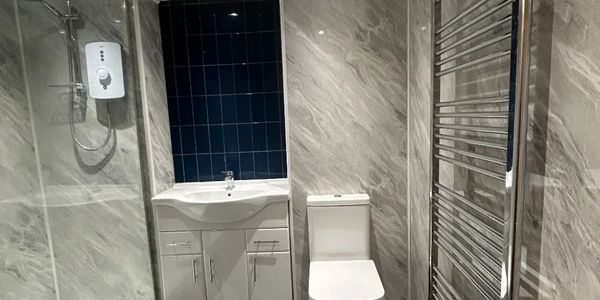 Modern bathroom with shower, sink, toilet, and heated towel rail.