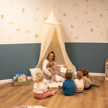A woman reading to children in a cozy room with a canopy tent.