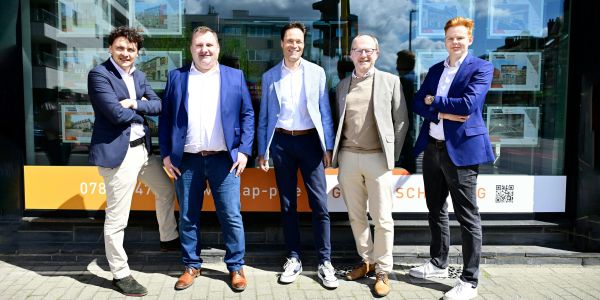 Five men in business casual attire standing outdoors.
