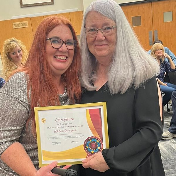 Two women smiling, holding a certificate of appreciation.