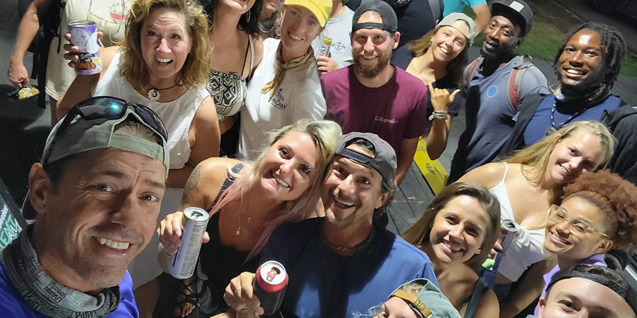 Group of friends smiling and posing with drinks at night.
