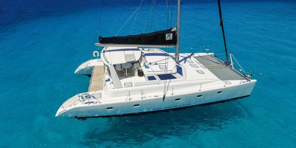 White catamaran sailing on clear blue waters.