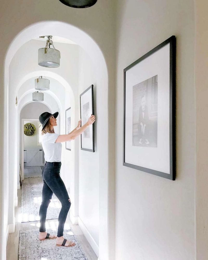 Woman hangs a picture frame in her home.