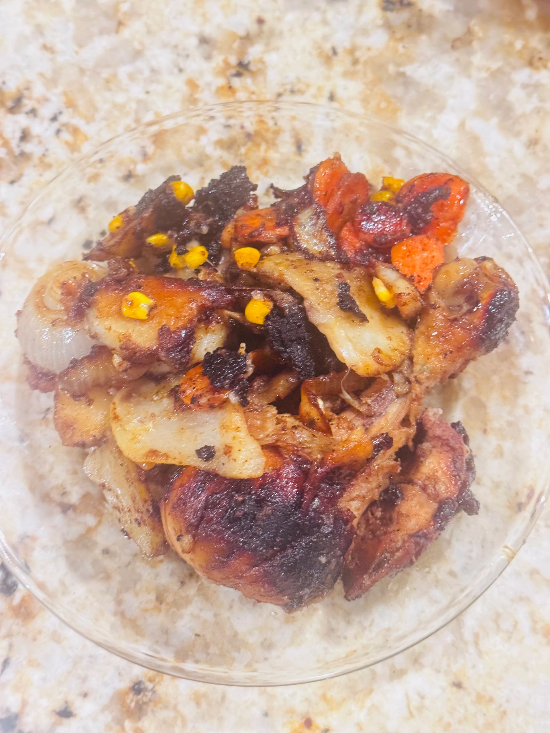 A plate of charred roasted vegetables with corn, carrots, and onions.