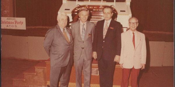 Four men posing at an annual Christmas party.