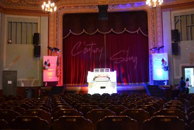 Empty theater with illuminated piano on stage.