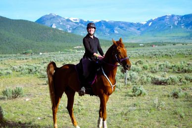 Person horseback riding in a scenic mountainous landscape.
