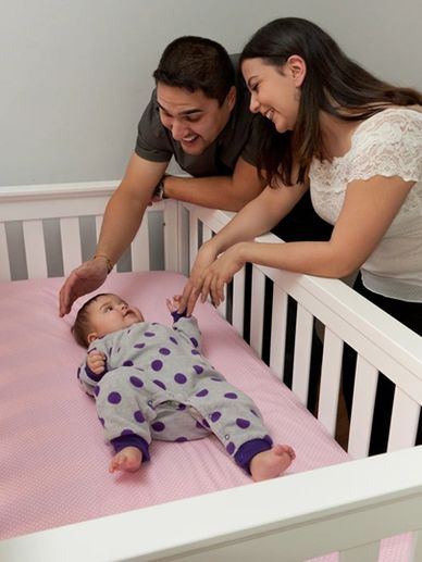 Parents happily interacting with their baby in a crib.