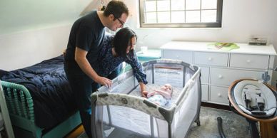 Parents lovingly watch their baby in a cozy nursery.