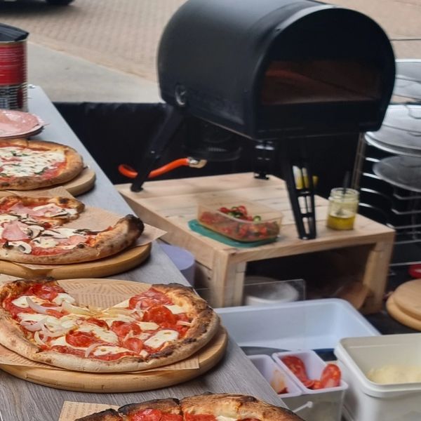 Wood-fired pizza oven with freshly baked pizzas on wooden boards.