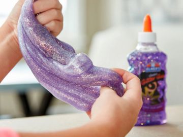 Hands stretching purple glitter slime.