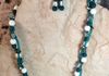Dark turquoise colored coral beads with glass and abalone chips. Double strand. Earrings included. Length 25 in. Item # 19-1-19. Price $20.00