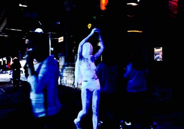 Person dressed in white glowing costume at night.