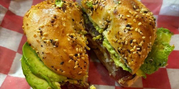 Queen BAE bagel breakfast sandwich features egg, avocado, and bacon on an everything bagel.