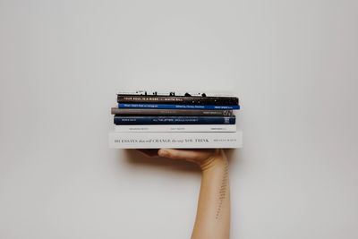 Image of a single hand holding a stack of books.