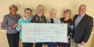 Group of six smiling people holding a large check for $2,400.