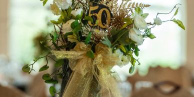 Elegant floral centerpiece with a golden 50th anniversary decoration and bow.