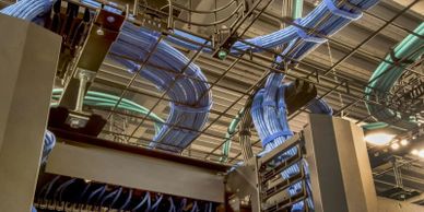 Blue network cables organized on ceiling cable trays in a data center.