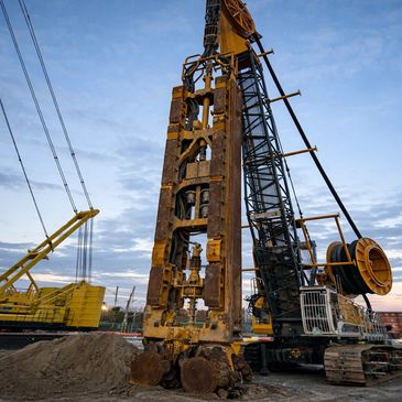 Large yellow drilling rig at a construction site during dusk.