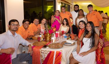Group of people enjoying a festive dinner with bright decorations and coordinated outfits.