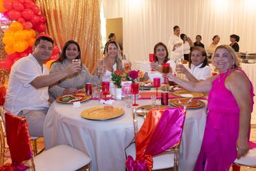 Group of six people raising glasses at a festive dinner table.