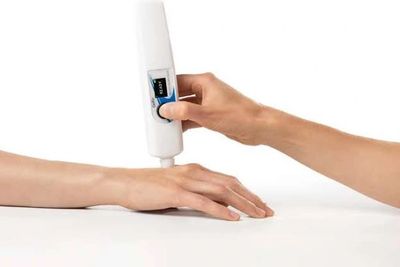A person applying cream to another's hand using a dispenser.