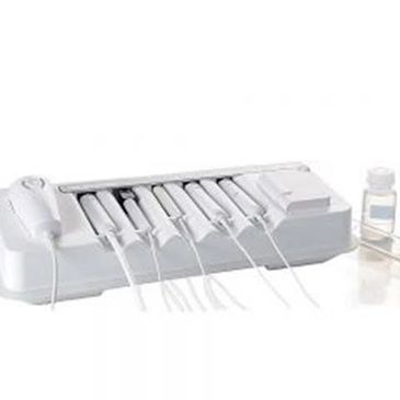 White dental ultrasonic scaler machine with handpieces and a liquid bottle.