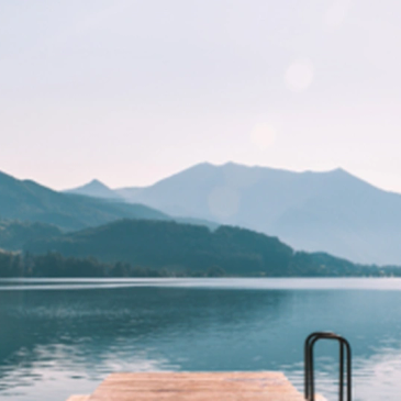 Serene lake with mountains in the background and a wooden dock in the foreground.