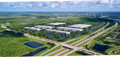 Aerial view of a highway interchange near industrial warehouses and green land.