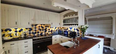 Oak kitchen that has been sprayed in a cream colour finish with yellow and blue tiled splash back