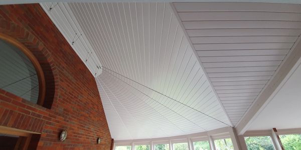 an oak ceiling that has been sprayed in white to contrast the orange brick walls