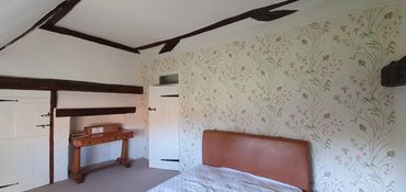 Heritage property with floral wallpaper and neuteral toned walls and dark oak beams