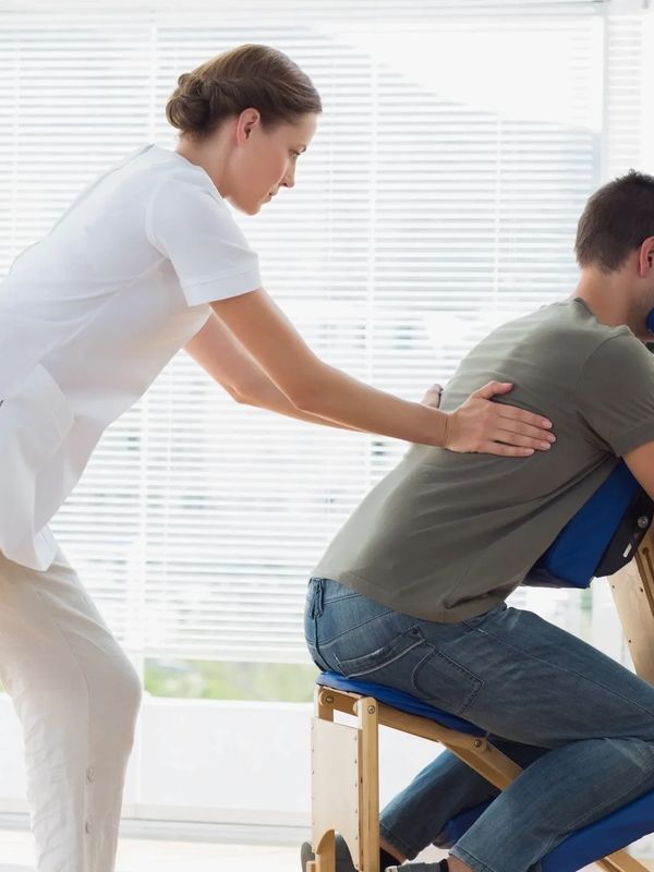 therapist administering seated upper body massage to a client in a corporate onsite workplace settin