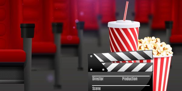 Movie theater seats with popcorn, soda, and a clapperboard in focus.