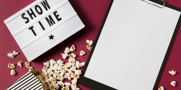 Popcorn spilled next to a blank clipboard and a lightbox reading 'SHOW TIME'.