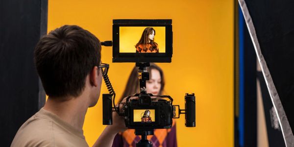 Photographer capturing a model against a yellow backdrop.