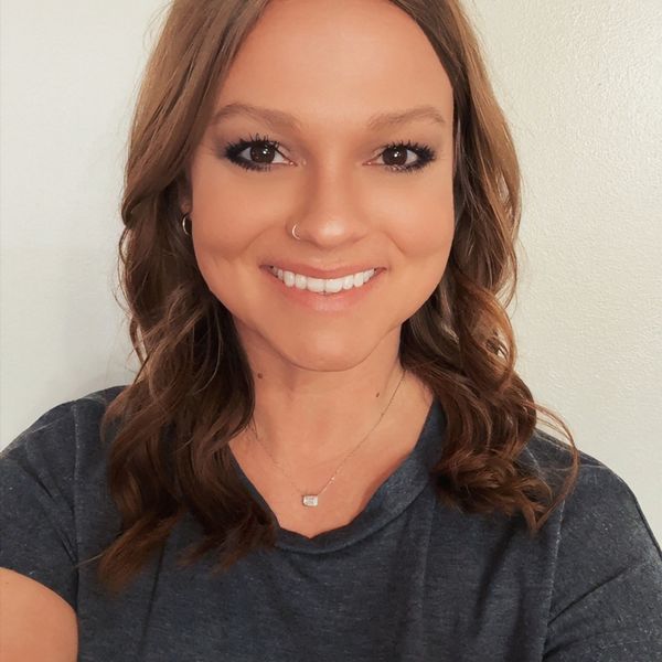 Smiling woman with wavy brown hair and a nose ring.