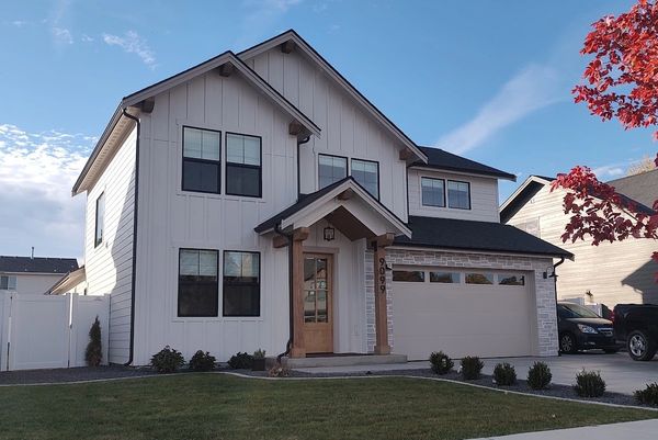 Modern two-story white house with black windows and wooden door.