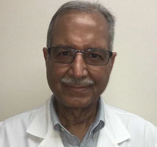 Portrait of an elderly man in glasses and white coat.