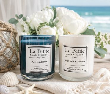 Two scented candles in glass jars by the beach.