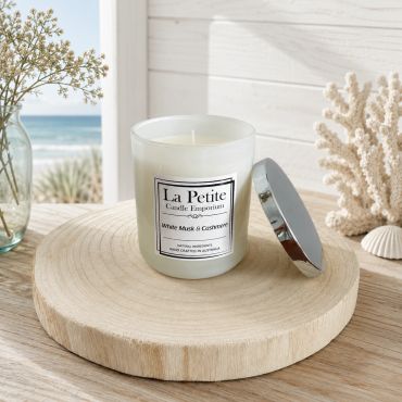 La Petite scented candle in a cozy beach setting.